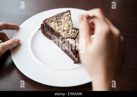 Close-up di donna di mano che tiene la forcella per pasticceria al cioccolato Foto Stock