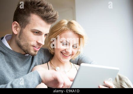 Felice coppia giovane con tavoletta digitale in cafe Foto Stock