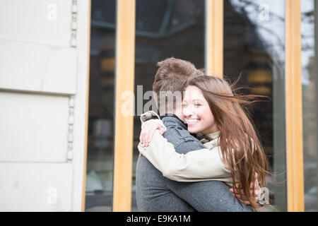 Vista laterale della coppia romantica abbracciando fuori cafe Foto Stock