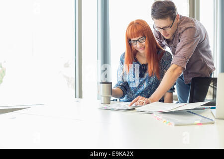 Gli imprenditori di analizzare file insieme alla scrivania in ufficio creativo Foto Stock