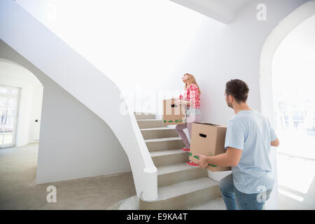 Giovane che trasportano contenitori per il trasloco su per le scale nella nuova casa Foto Stock
