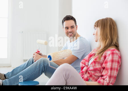 Giovane prendendo pausa dal dipinto nella nuova casa Foto Stock