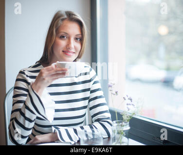 Ritratto di donna sorridente avente caffè al tavolo Foto Stock