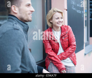 Felice coppia giovane seduto fuori cafe Foto Stock