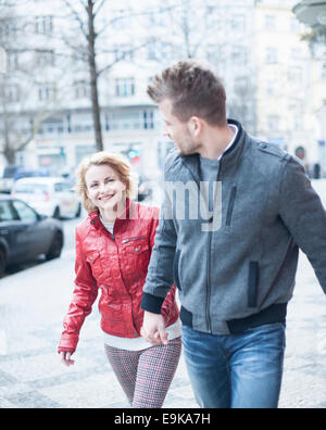 Felice coppia giovane tenendo le mani mentre si cammina sulla strada di città Foto Stock