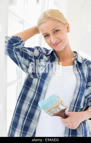 Ritratto di donna bella tenendo il pennello nella nuova casa Foto Stock