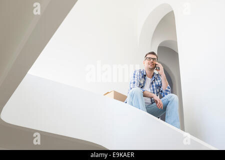 Basso angolo di visione dell'uomo tramite telefono cellulare nella nuova casa Foto Stock