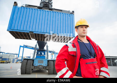 Fiducioso lavoratore di sesso maschile in piedi nella parte anteriore del veicolo di trasporto merci in cantiere
