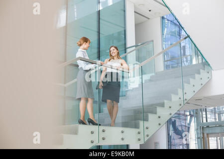 Imprenditrici conversando su passi in ufficio Foto Stock