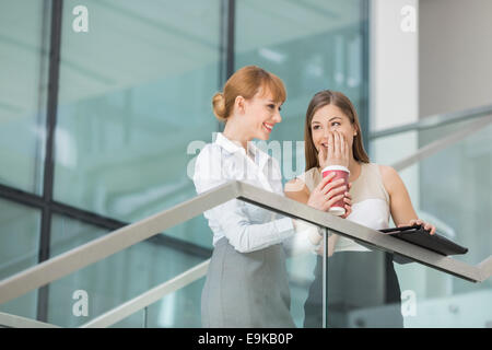 Imprenditrici spettegolare pur avendo caffè sui passi in ufficio Foto Stock