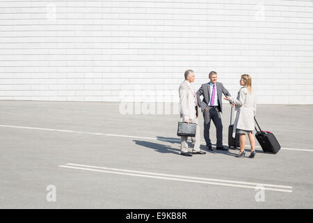 Imprenditori con bagagli comunicando su strada Foto Stock