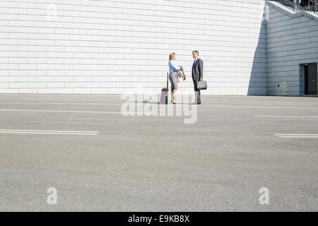 Imprenditori con bagagli parlando su strada Foto Stock