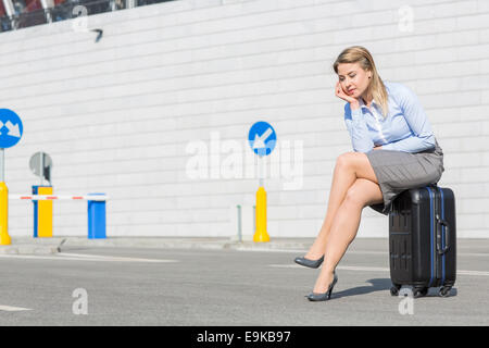 Stanco imprenditrice seduti sui bagagli Foto Stock