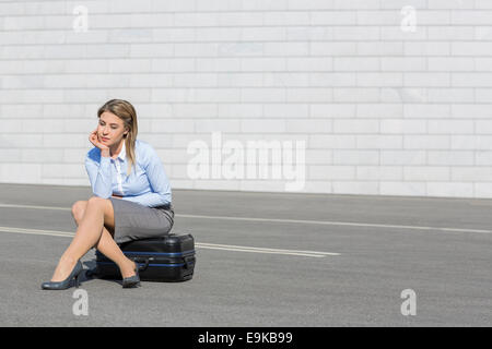 Stanco imprenditrice seduti sui bagagli Foto Stock