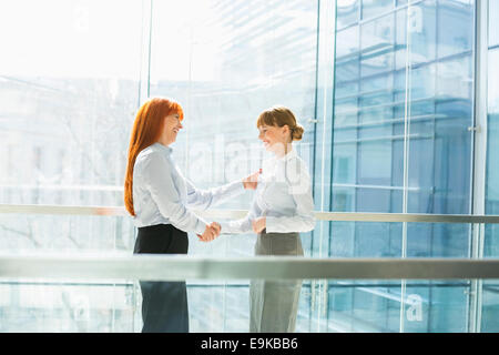 Felice imprenditrici stringono le mani in office Foto Stock