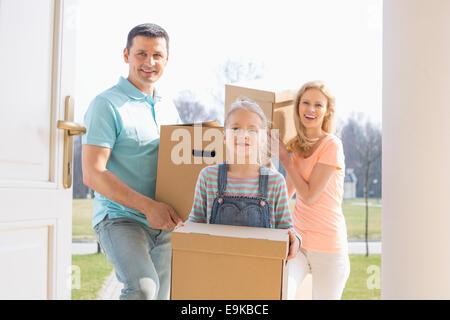 La famiglia felice con scatole di cartone immettendo il nuovo home Foto Stock