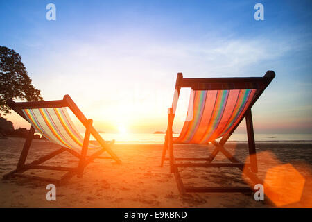 Sedie a sdraio sulla spiaggia deserta oceanside a incredibili sunrise. Foto Stock