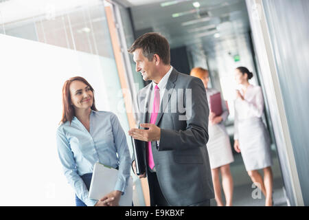 Imprenditore parlando con la collega di sesso femminile mentre si cammina nel corridoio di office Foto Stock