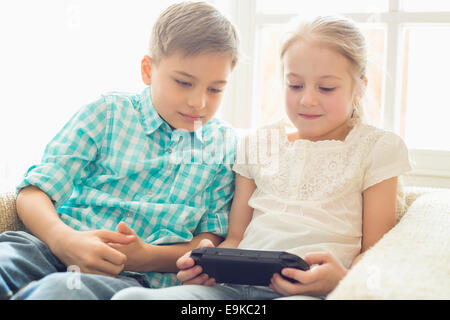 I fratelli giocando hand-held video gioco a casa Foto Stock