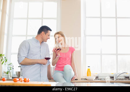 Coppia felice guardando ogni altro mentre si beve il vino rosso in cucina Foto Stock