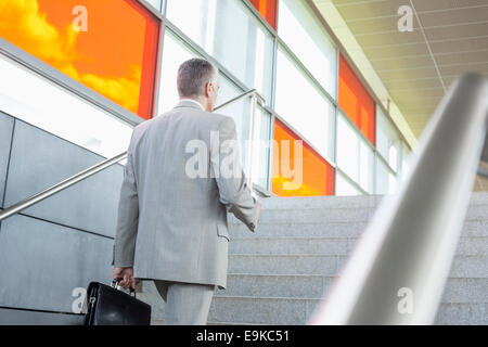 Vista posteriore di mezza età imprenditore salendo le scale nella stazione ferroviaria Foto Stock