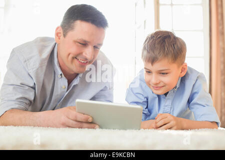 Padre e figlio utilizzando il tavolo digitale sul pavimento a casa Foto Stock