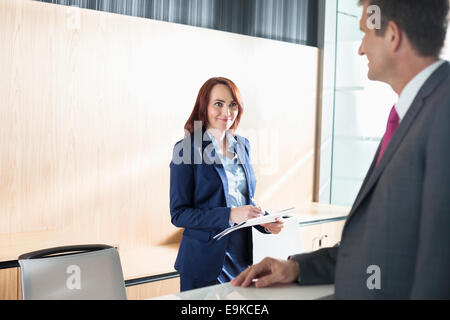 Imprenditore parlando con la receptionist di office Foto Stock