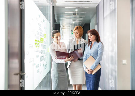 Imprenditrici con le cartelle di file di discutere nel corridoio di office Foto Stock