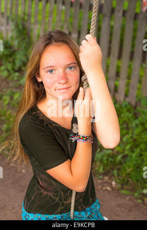 Bella ragazza teen basculante in una corda swing in campagna. Foto Stock