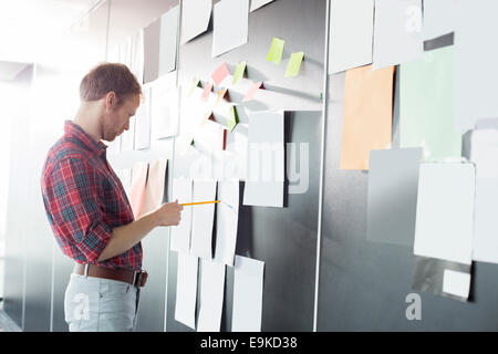 Imprenditore analizzando i documenti sulla parete presso il creative office Foto Stock