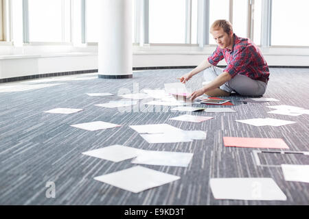 Imprenditore analizzando le fotografie mentre è seduto sul pavimento presso il creative office Foto Stock