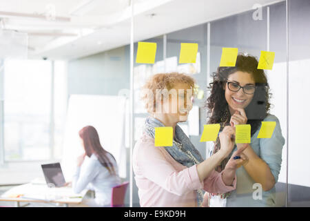 Le donne d'affari il brainstorming con sticky notes in ufficio Foto Stock