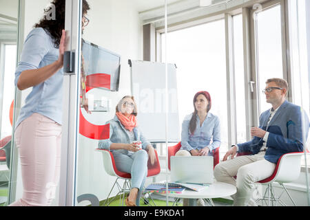 La gente di affari guardando al collega di sesso femminile in piedi nella porta scorrevole Foto Stock