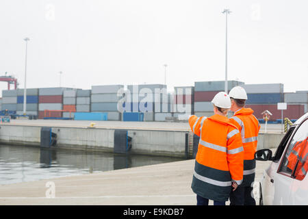 I lavoratori di abbigliamento protettivo esaminando il carico in cantiere di spedizione Foto Stock