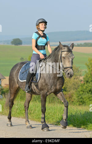 Giovane pilota sul dorso di un pony Connemara indossando un paraschiena duing ride out Foto Stock
