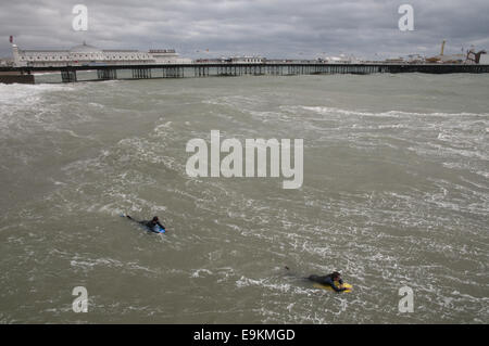 Due surfisti in freddo e ruvido acque fuori la spiaggia di Brighton, Inghilterra Foto Stock