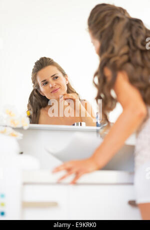 Ritratto di felice giovane donna viso verifica le condizioni della pelle Foto Stock