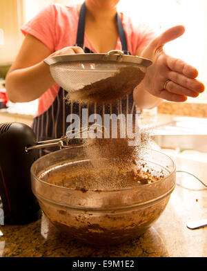 Essendo la farina setacciata in una torta facendo recipiente da un fornaio. Foto Stock