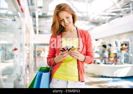 Cliente femmina con carte in plastica in piedi in the mall Foto Stock