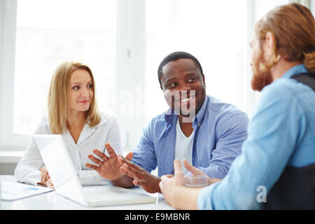 Gruppo di collaboratori nell'informale che interagiscono su business meeting Foto Stock