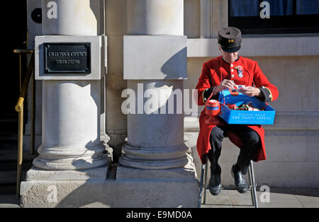 Londra, Inghilterra, Regno Unito. Chelsea pensionato papaveri di vendita al di fuori della vecchia guerra Edificio per uffici a Whitehall Foto Stock