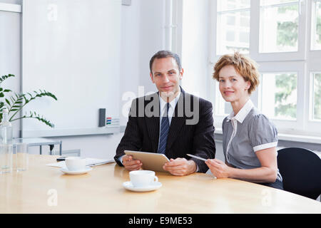 Un imprenditore e imprenditrice utilizzando una tavoletta digitale in una riunione Foto Stock