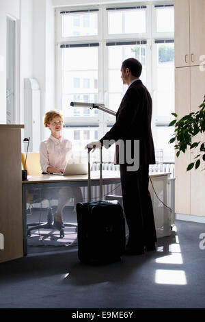 Viaggia per lavoro parlando a una imprenditrice seduti ad una scrivania Foto Stock