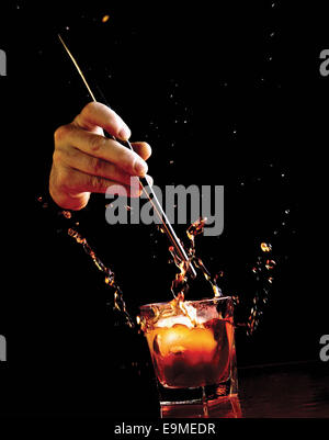 La caduta di mano il ghiaccio in whiskey su sfondo nero Foto Stock