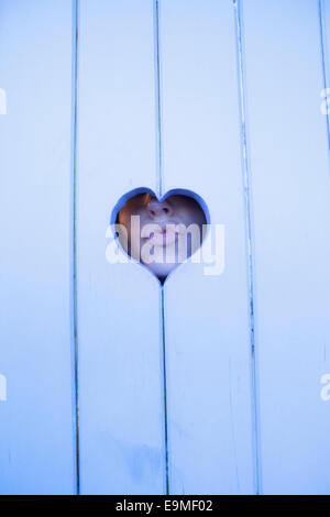 Close-up di donna raggrinzamenti labbra attraverso il cuore di legno di forma Foto Stock