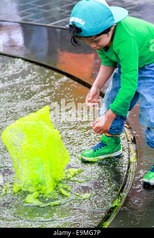 DORDRECHT, Paesi Bassi - 20 Maggio 2014: bambini che giocano in verde acqua colorata nella fontana sulla piazza principale durante la celebrazione Foto Stock