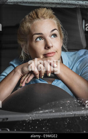 Premurosa donna appoggiata sul volante in auto Foto Stock