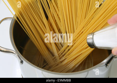 Cucinare gli spaghetti tagliatelle pasta pasto: Salatura acqua nella pentola Foto Stock