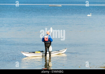 Uomo in piedi accanto alla sua canoa sul fiume stour Manningtree Essex UK Foto Stock