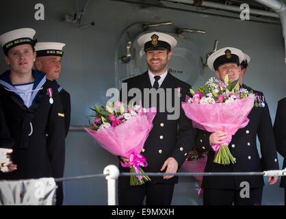 Ufficiali con mazzi di fiori di attendere pazientemente a bordo come il tipo 23 fregata HMS Richmond ritorna a Portsmouth Royal Navy Bas Foto Stock